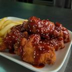 Crispy kip in saus met Korean Fried Chicken Taste, gegarneerd met sesam bij gerserveerd met een portie friet